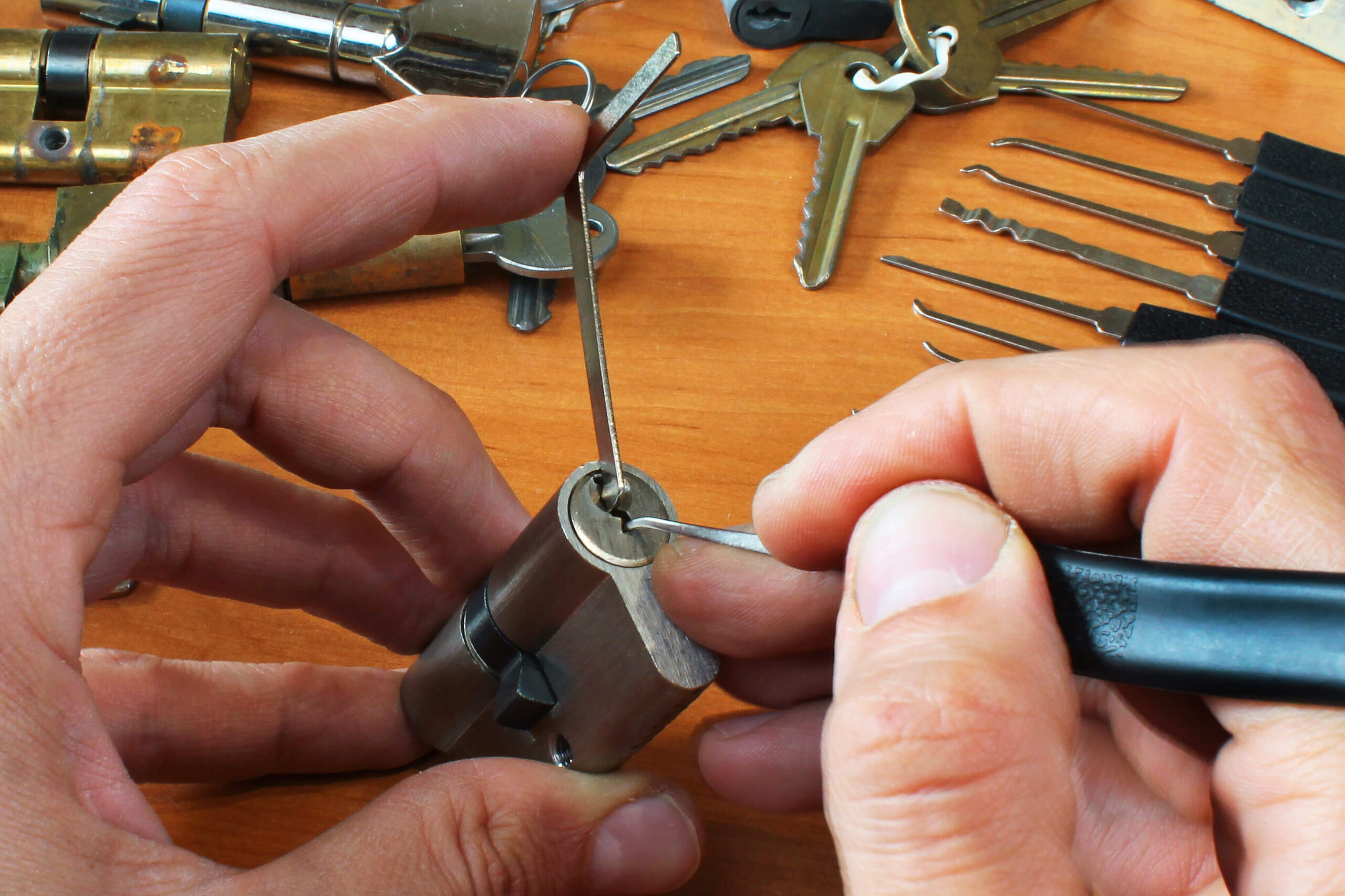 Hands using lockpicks on a lock, tools in background.